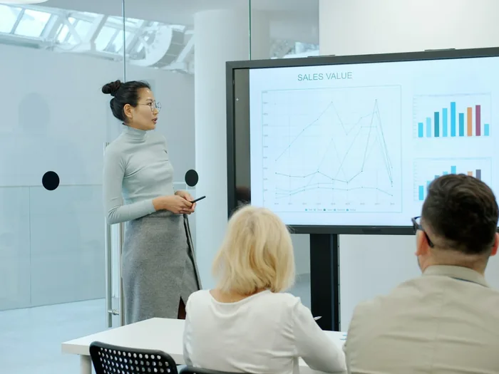 Vrouw presenteert cijfers op een scherm aan haar team