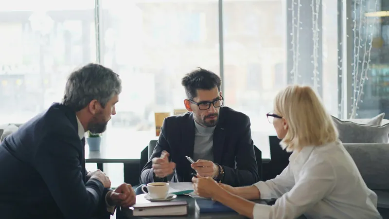 Drie mensen in overleg aan een tafel