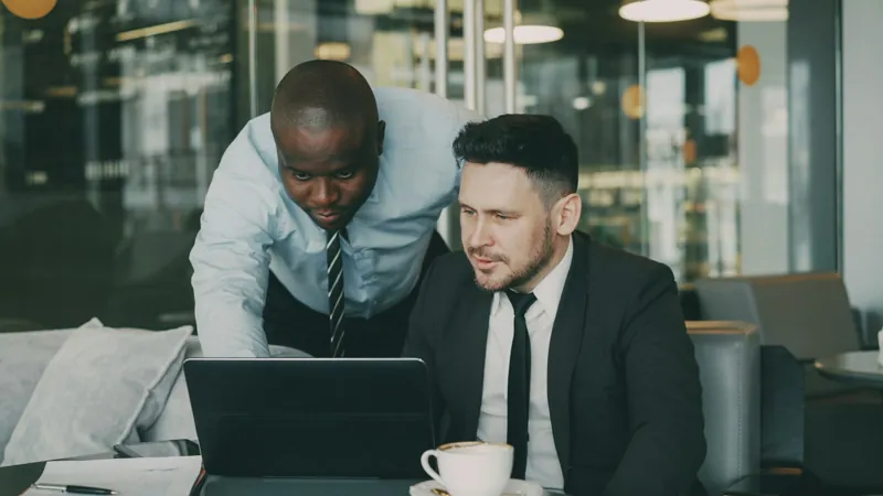 Twee mannen bekijken samen een laptopscherm