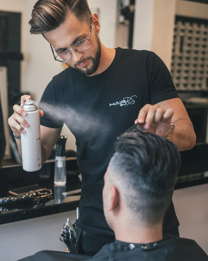 A barber working on a customer's hair in his salon