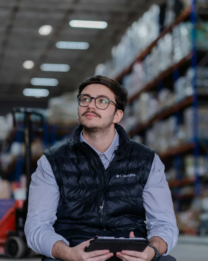 A man with a tablet in a warehouse with racking