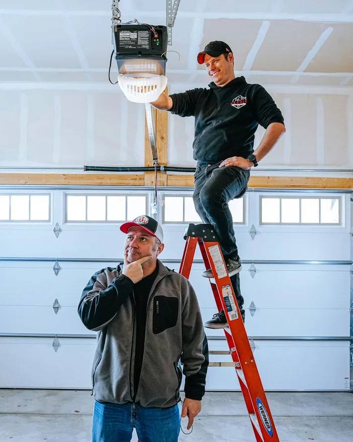 Two installers at work in a garage, one on a ladder